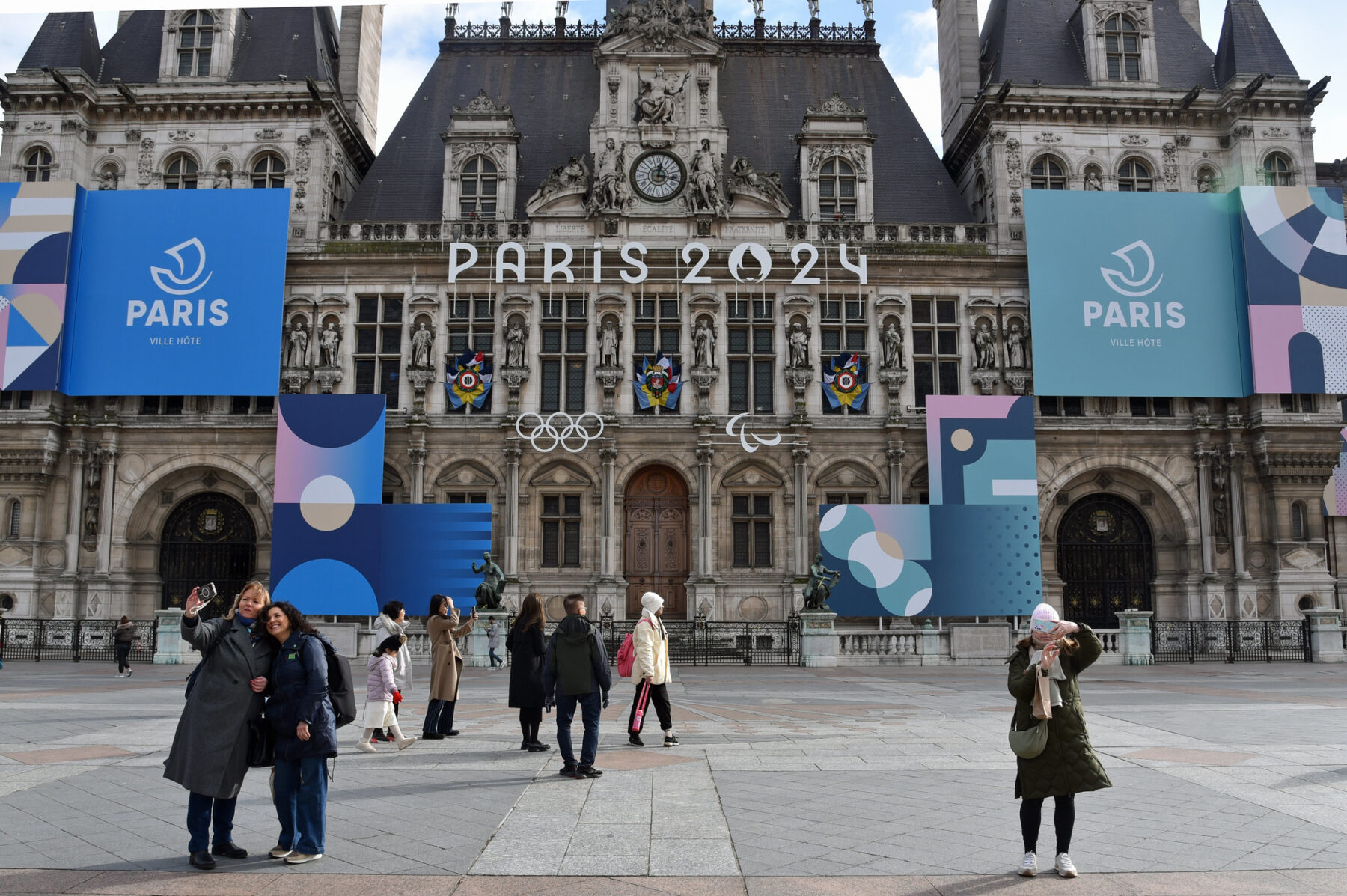 Photo of L’hôtel de Ville with signage for Paris 2024 Olympics with tourists taking photos